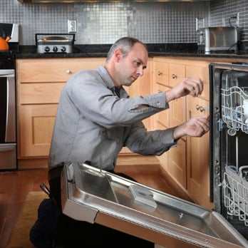 Appliance repair technician fixing dishwasher