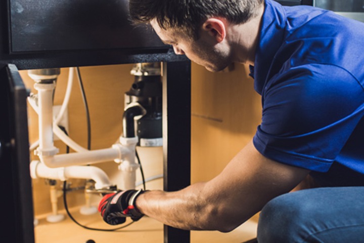 Plumber fixing under sink pipes