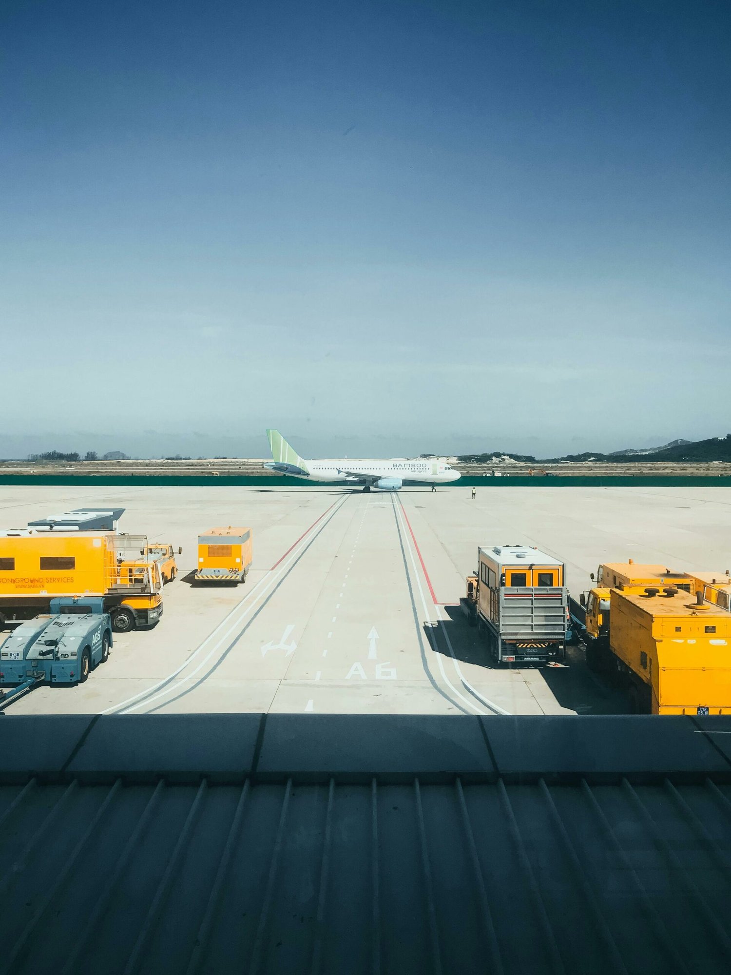 Plane between trucks. A plane between yellow trucks and work vehicles on a runway.