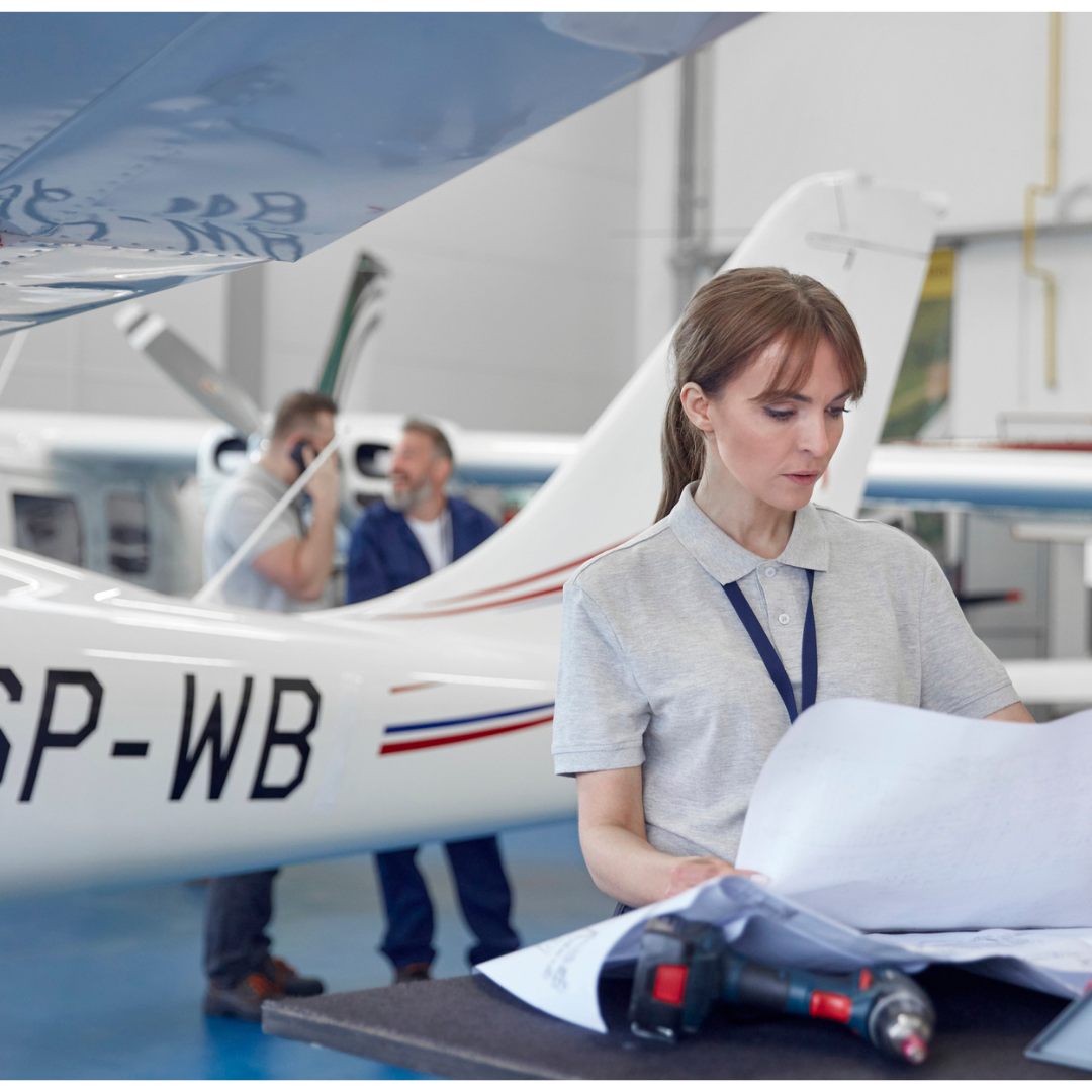 Aerospace engineer reviewing plans Aerospace engineer reviewing plans in front of a plane.