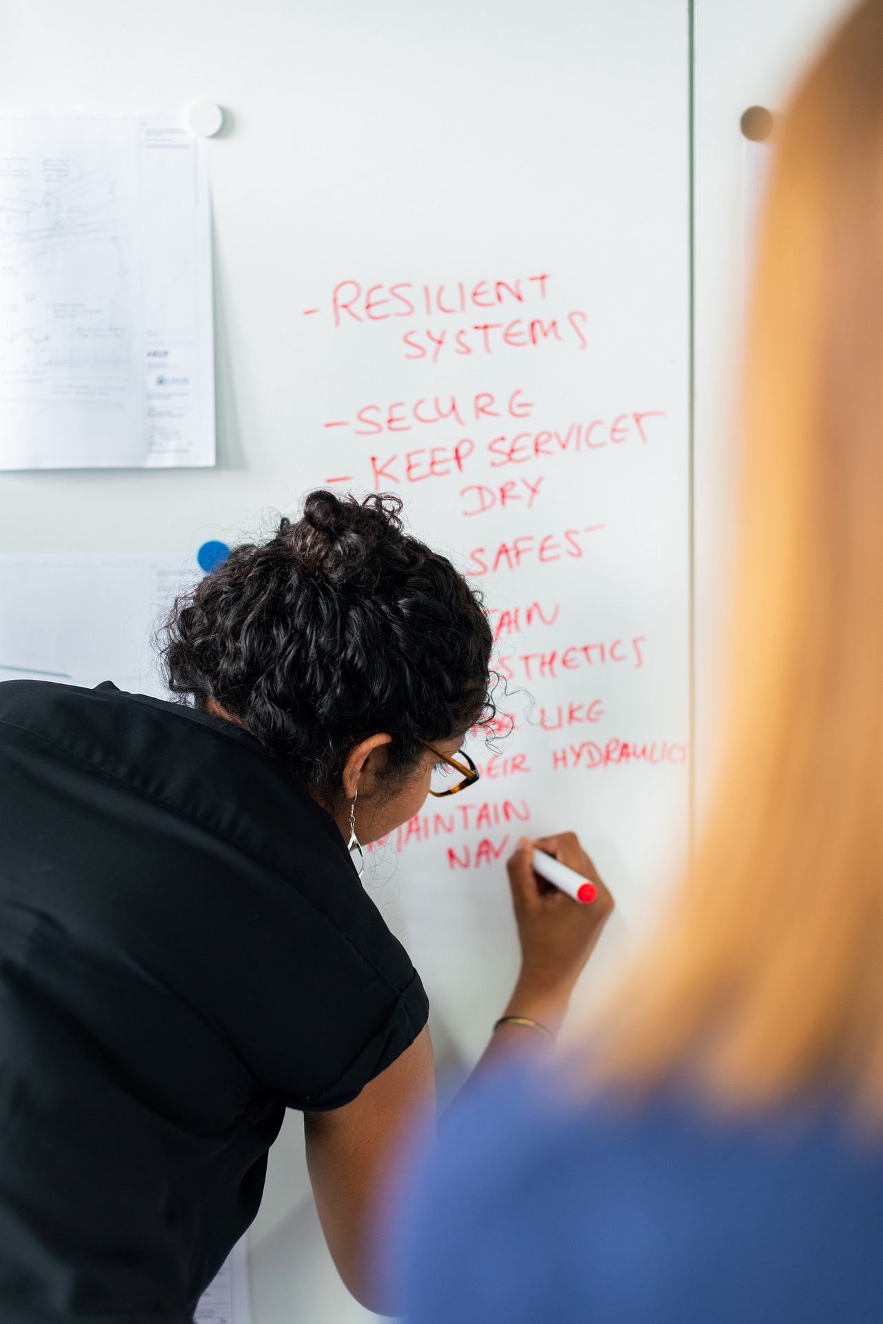 Systems engineer working Systems engineer listing down system components on a whiteboard.