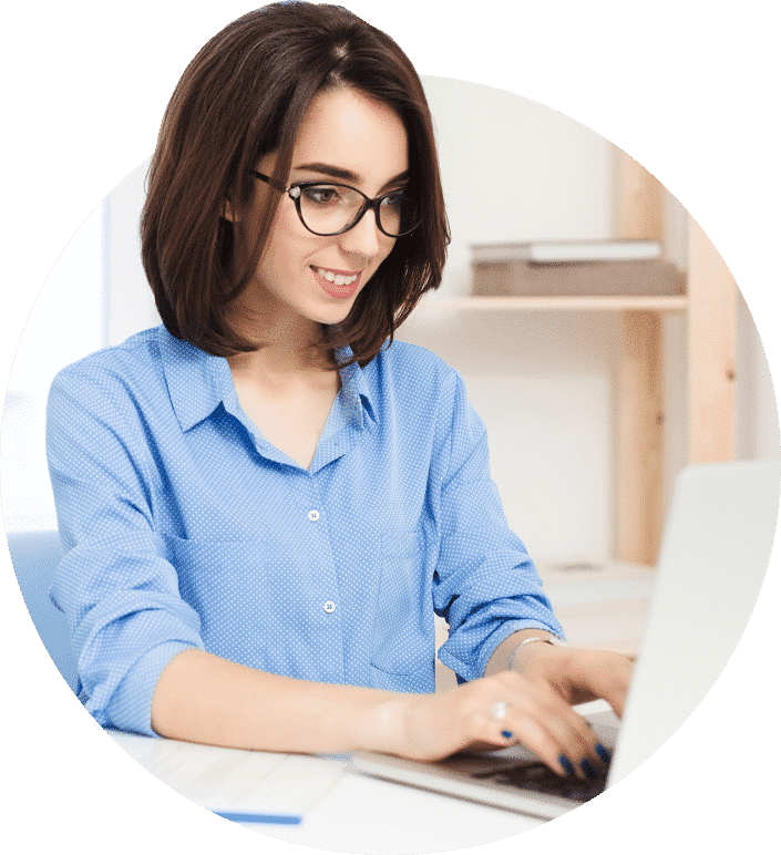 A woman wearing glasses is working on a laptop.