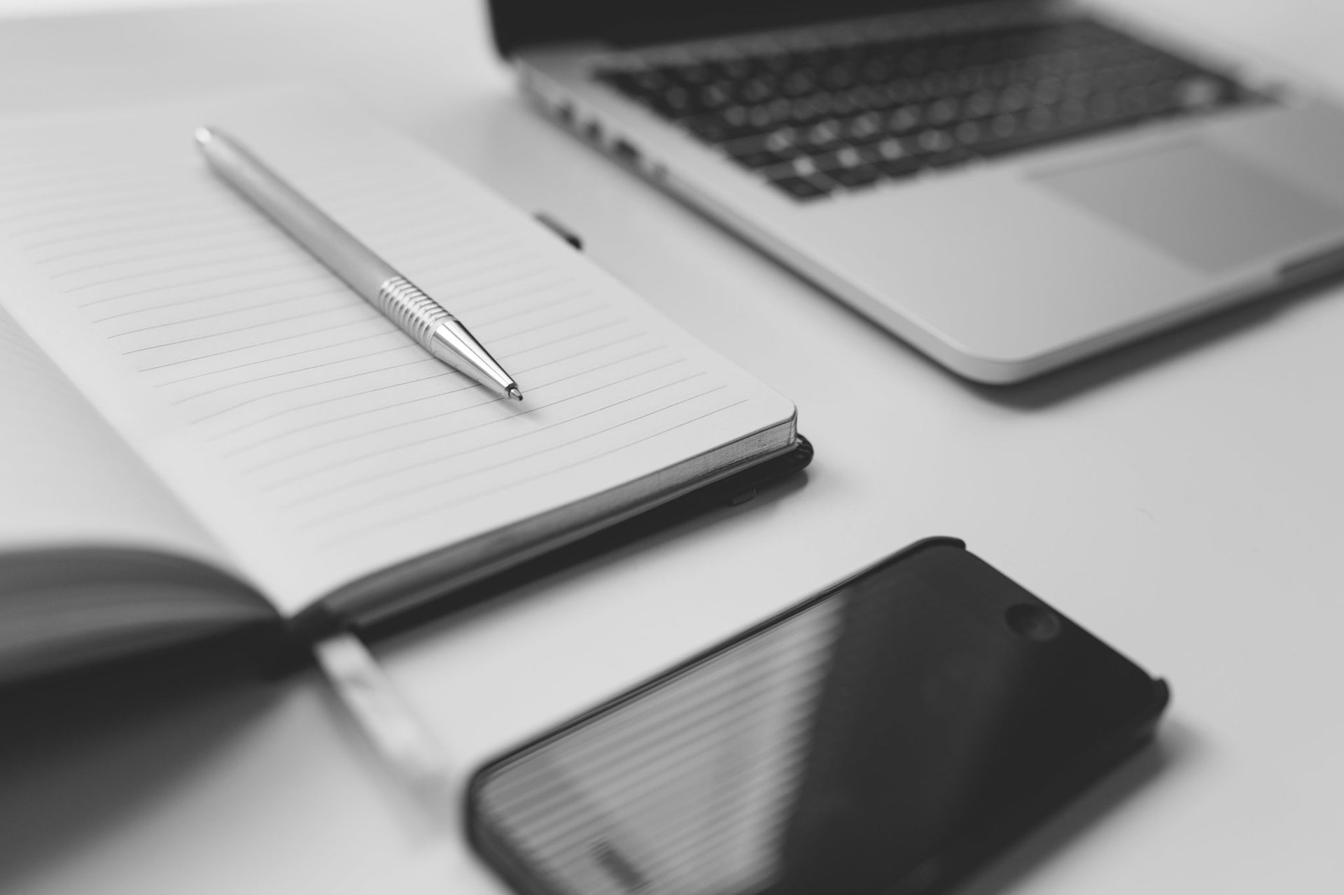 A successful black and white photo featuring a cell phone and pen on a desk.