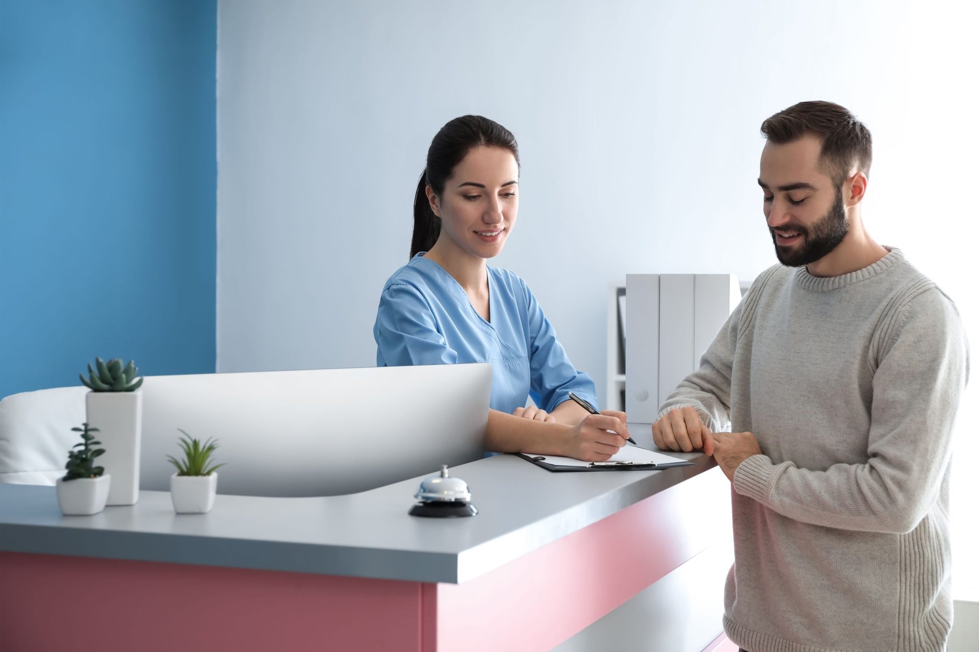 A man and a woman at the front desk of a medical office.