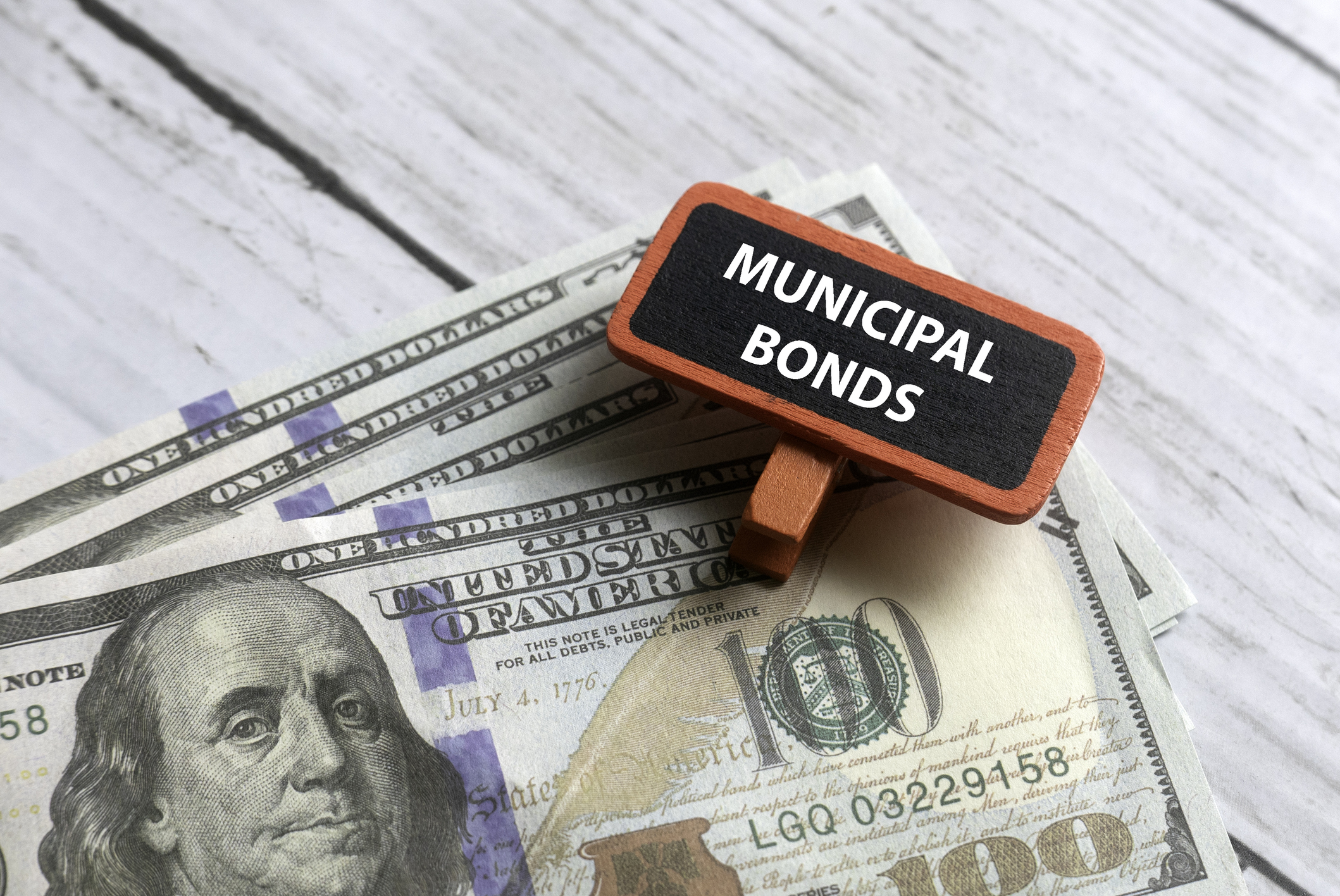 Selective focus of dollar notes and red tag written with MUNICIPAL BONDS on white wooden background | Alpine Hill Advisors img-7