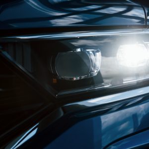 Front part of brand new modern blue car. Parked at showroom. Reflection in the headlights Front part of brand new modern blue car. Parked at showroom. Reflection in the headlights
