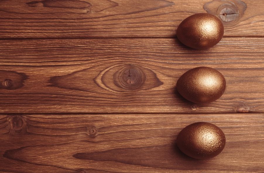 three golden eggs in wooden background