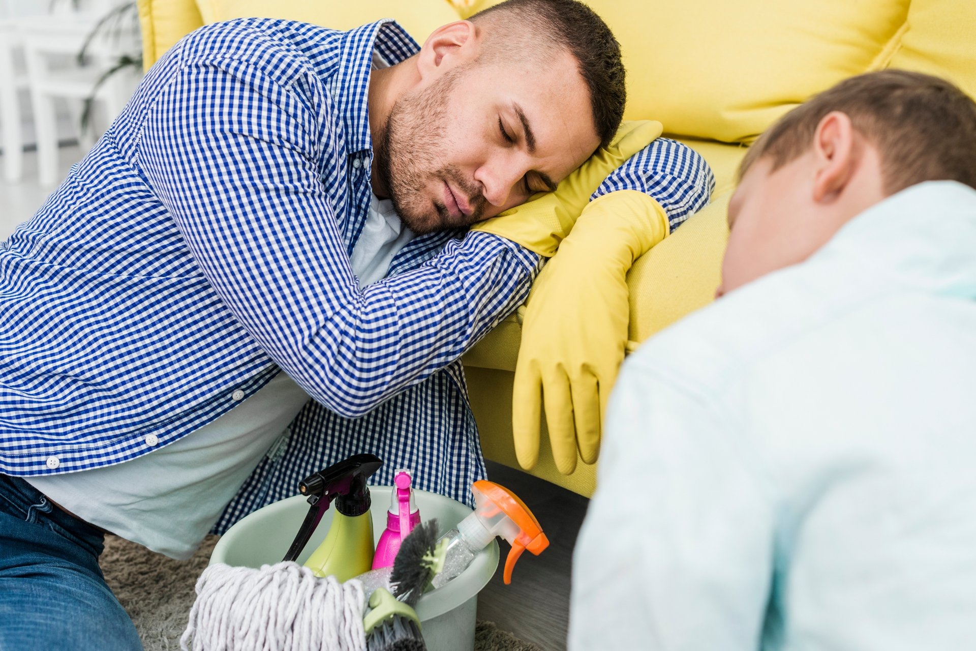 The Essential End-of-Lease Checklist for Getting Your Full Bond Back 1 Exhausted cleaner in yellow gloves resting on couch after intensive cleaning session with mop and caddy nearby Mermaid Waters