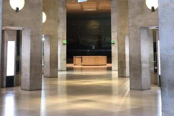 Shopping Centres 1 AustClean shopping centre cleaning – spacious, light-filled hall with tall stone columns, round wall lights, and a polished floor, with a wooden reception desk and mural, showcasing meticulous maintenance by professional retail and commercial cleaners in Australia.