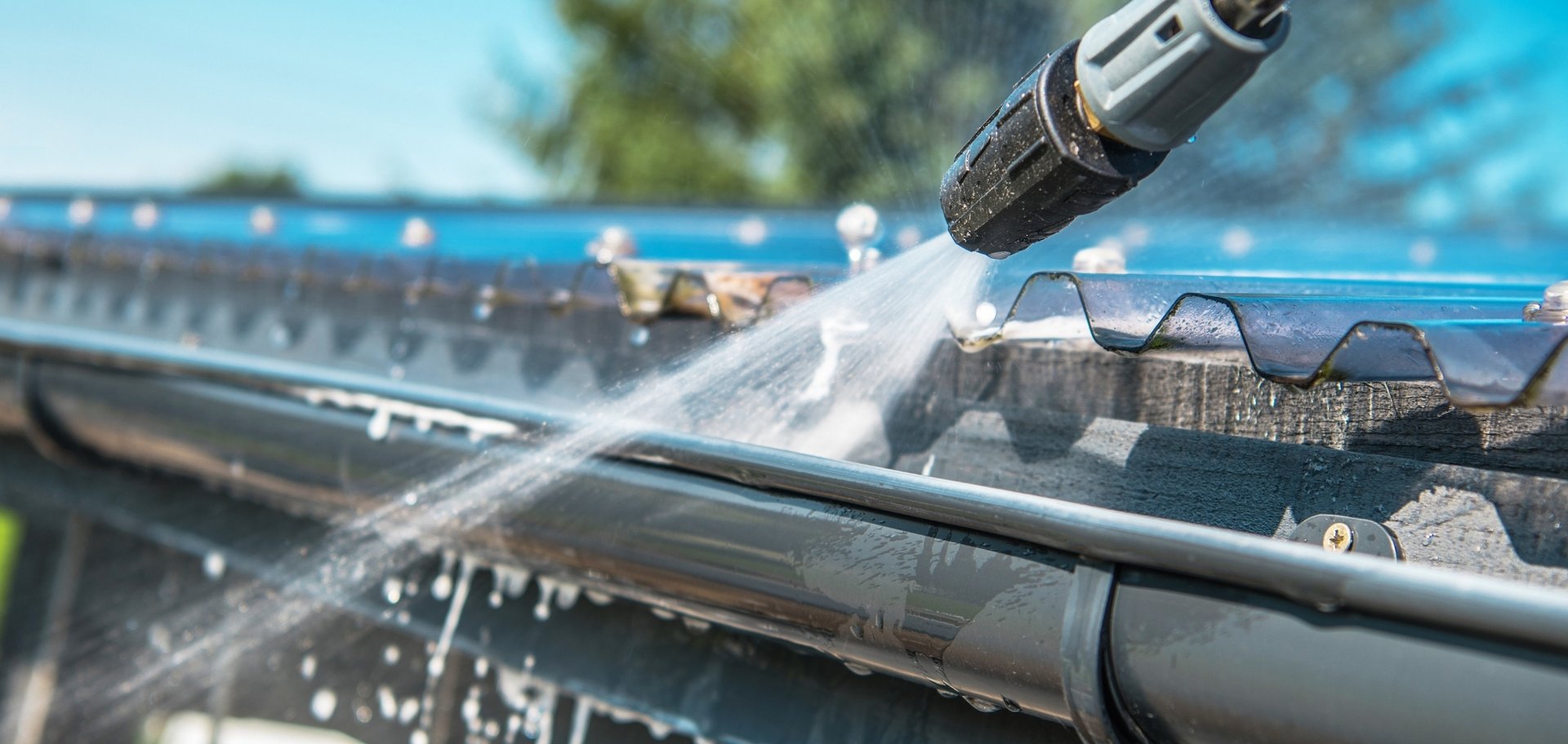 Gutter Cleaning 3 AustClean professional gutter cleaning in action – close-up of a technician using a pressure washer to spray water onto roof gutters, with droplets visible, showcasing advanced cleaning for Australian property maintenance.