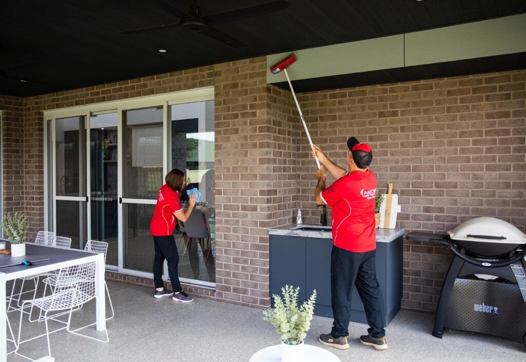 What Does an End of Lease Clean Usually Include? Your 2026 RTA-Aligned Guide 4 Professional exterior building cleaning service with technicians washing brick walls and windows using extension cleaning equipment