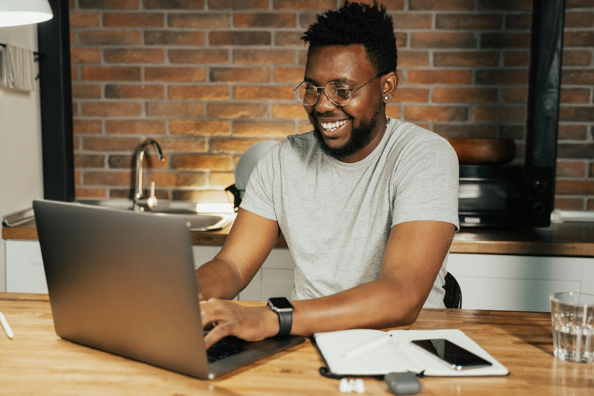 Photo by Tima Miroshnichenko African American man smiling while working remotely on laptop from home office