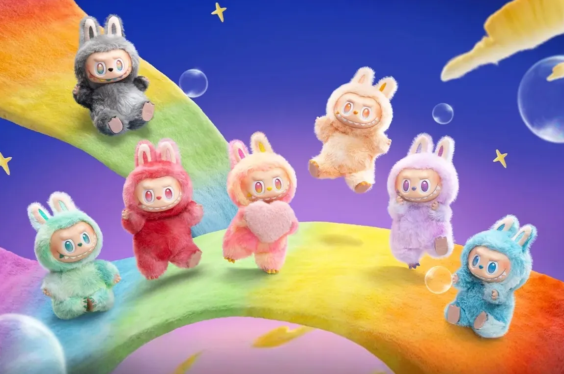 Үлгэрийн баатар Лабубугаас санаа авсан, туулайн чихтэй, том нүдтэй долоон өнгөт тансаг тоглоом, арын хэсэгт бөмбөлөгүүд, зөөлөн үүлнүүдтэй, мөрөөдөмтгий, одтой хөх, нил ягаан тэнгэрийн эсрэг эрч хүчтэй солонгын зам дээр суугаад зогсоно. - Business.MN