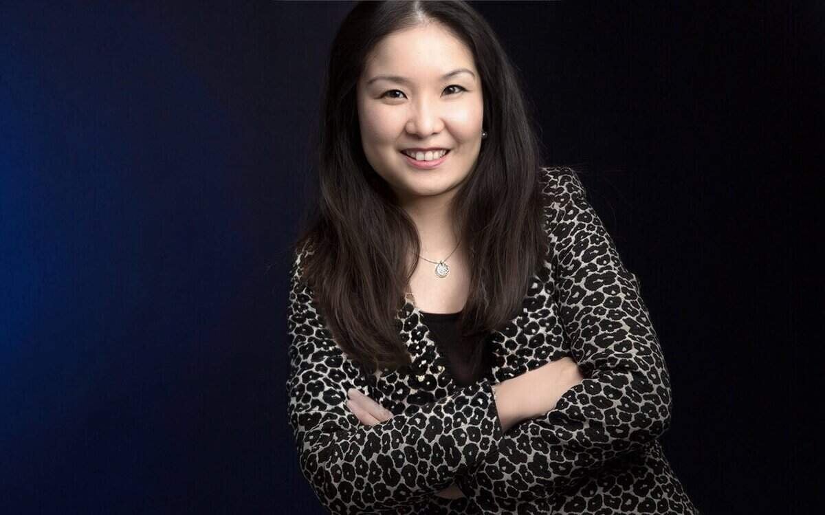 Харанхуй дэвсгэр дээр амжилттай энтрепренерийн итгэлийг илэрхийлж, ирвэсний хээтэй хүрэм өмссөн гараа зөрүүлэн инээмсэглэж буй эмэгтэй. - Business.MN