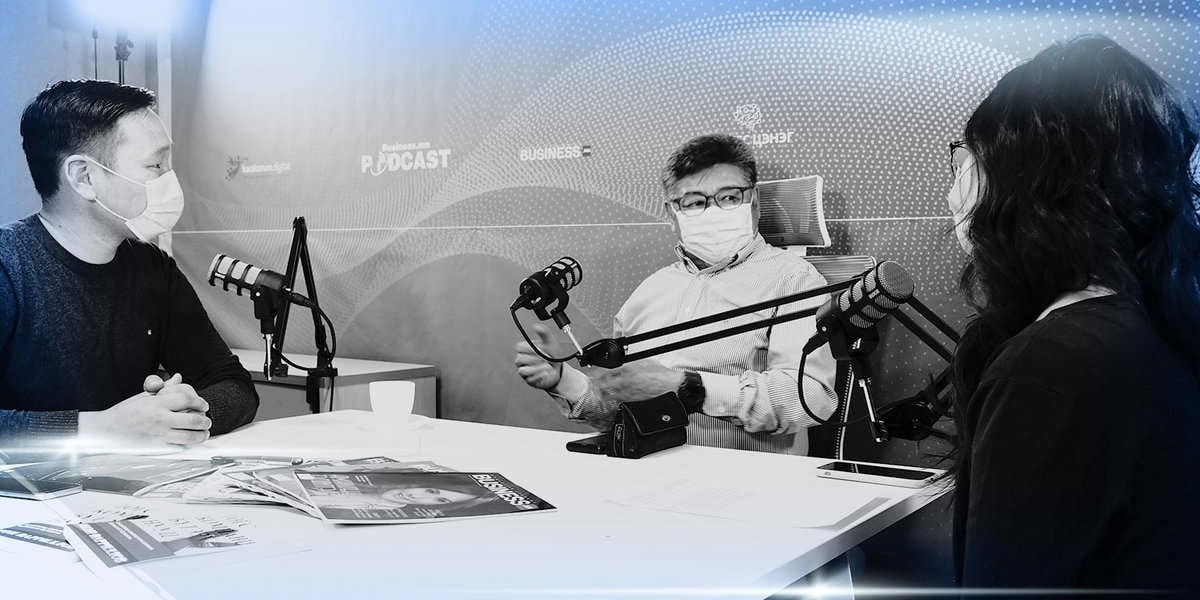 Хар, цагаан зураг дээр гурван энтрепренеров нүүрний маск зүүж, подкаст студид хэлэлцүүлэг хийж байгааг харуулж байна. Тэд микрофон, чихэвч, цаас, сэтгүүл дэлгэсэн ширээний эргэн тойронд сууж байна. Нэг хүн гараараа дохиж байна. - Business.MN