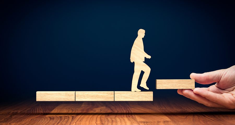 Модон хайчилбар нь бизнес эрхлэгчийн аяллыг бэлгэддэг өндөр блок руу гарч байна. Гараар барьсан өндөр блок нь шатаар авирах хуурмаг байдлыг бий болгодог. Хар хөх өнгийн дэвсгэр нь өнгөлсөн модон ширээний гадаргуугаас ялгаатай бөгөөд бизнесийн өсөлтийн мөн чанарыг илтгэнэ. - Business.MN