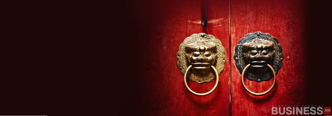 Улаан модон хаалганууд нь арслан толгойтой хоёр гоёл чимэглэлтэй, нэг нь алтаар, нөгөө нь бараан металлаар хийгдсэн байдаг. Арын дэвсгэр нь зүүн талд нь хатуу бараан өнгөтэй, баруун доод буланд "БИЗНЕС" гэсэн бичээстэй. - Business.MN