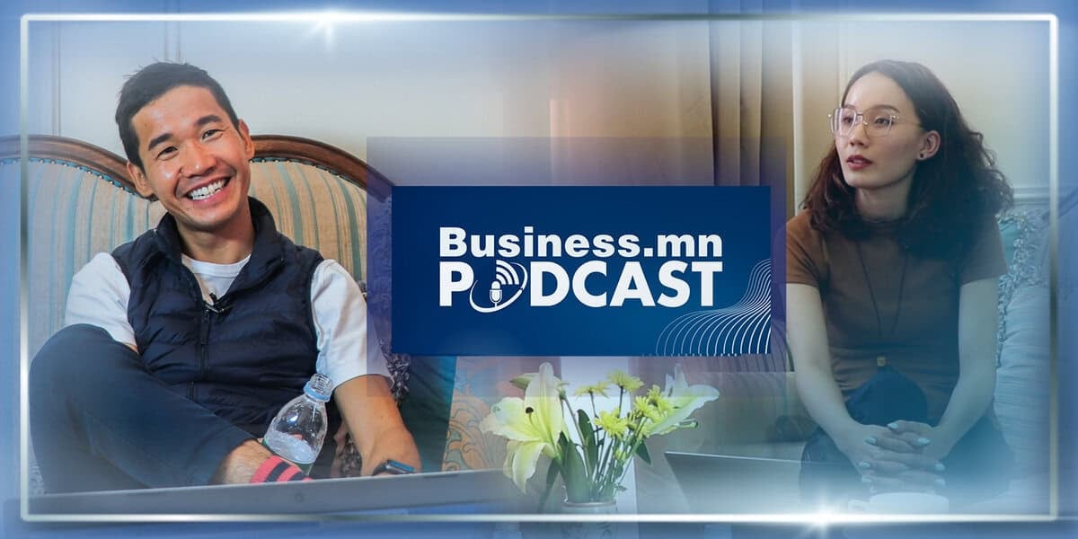 Тод гэрэлтэй өрөөнд хоёр хүн подкаст оролцож байна. Зүүн талд байгаа эрэгтэй усны сав барин инээмсэглэж, баруун талд байгаа эмэгтэй анхааралтай сонсож байна. Тэдний хооронд "Business.mn PODCAST" гэсэн бичээс харагдана. - Business.MN