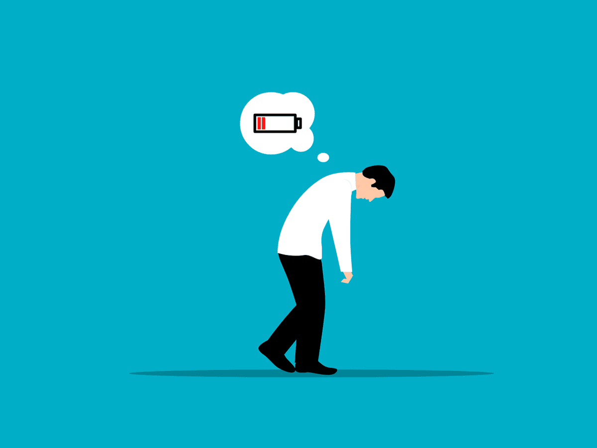 Illustration of a person in a white shirt and black pants, slouching with their head down. A thought bubble above shows a low battery icon, suggesting tiredness or exhaustion. The background is blue.