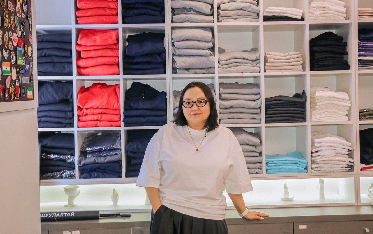 Эвхэгдсэн хувцасны тавиурын өмнө зогсож буй эмэгтэй. - Business.MN