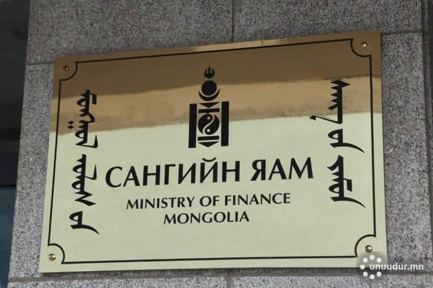 Хананд наасан тэгш өнцөгт хэлбэртэй алтан товруу нь монгол, англи зэрэг янз бүрийн үсгээр бичвэрийг харуулдаг. Англи хэл дээрх эх бичвэр нь "Монгол Улсын Сангийн яам" гэж бичсэн байна. Уг самбарт бичвэрийн дээгүүр гоёл чимэглэлийн эмблем байрлуулсан нь улс үндэстэн бизнес болон эдийн засгийн өсөлтийг хангахад тууштай зүтгэж буйг илэрхийлдэг. - Business.MN
