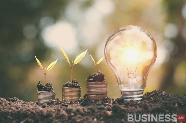 Гялалзсан гэрлийн чийдэнгийн дэргэд овоолсон зоосноос ургаж буй гурван жижиг ургамал нь бизнес болон компанийн өсөлт, шинэчлэлийг бэлэгддэг. - Business.MN