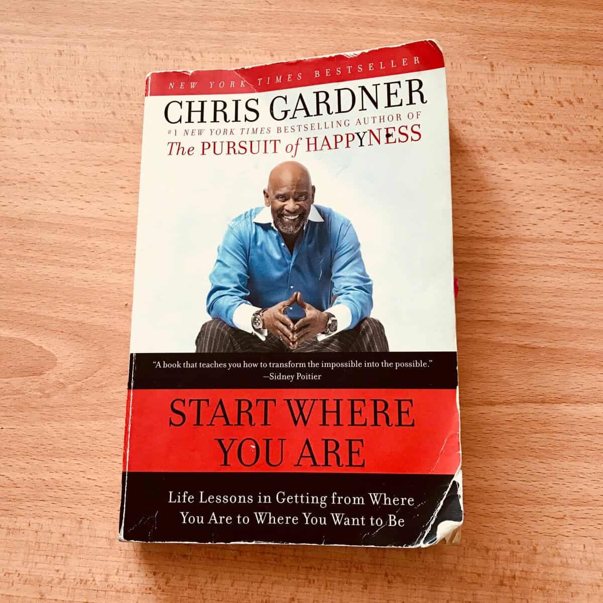 Зураг дээр Крис Гарднерийн "Чи байгаа газраасаа эхэл" номыг харуулжээ. Хавтасны нүүрэнд улаан, цагаан дэвсгэр дээр сууж буй хөх цамцтай инээмсэглэж буй хүн дүрслэгдсэн байна. Уг ном нь Нью Йорк Таймс сонины шилдэг борлуулалттай ном юм. - Business.MN