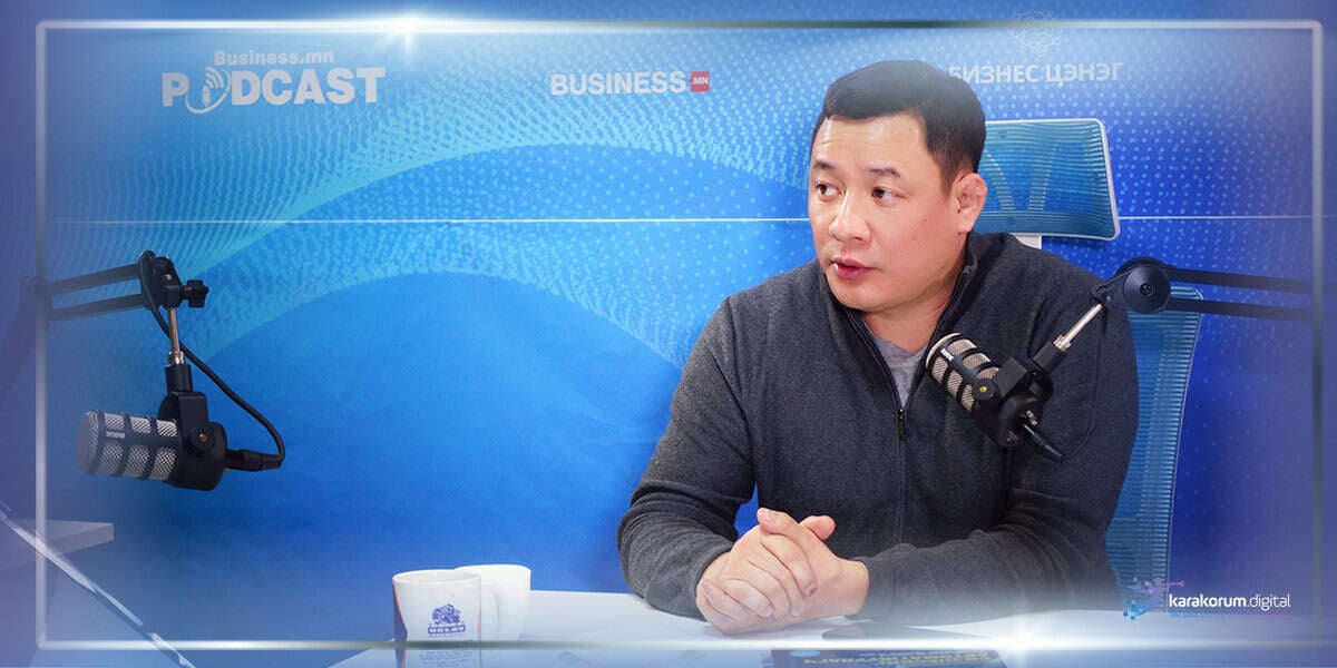 Энтрепренер подкаст студид сууж, ард нь "Business.mn PODCAST" гэсэн бичээстэй микрофон руу догдолж ярьж байна. - Business.MN