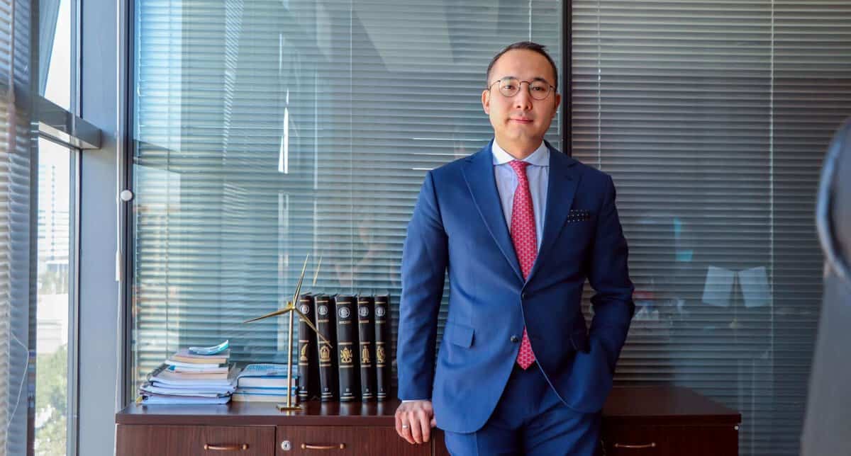 Цэнхэр костюм, улаан зангиа зүүсэн эр албан тасалгаанд ард нь шүүгээн дээрээ ном, бичиг баримттай зогсож байгаа нь компаниа бизнесийн өсөлтөд чиглүүлэхэд бэлэн энтрепренерийн сүнсийг илэрхийлдэг. - Business.MN