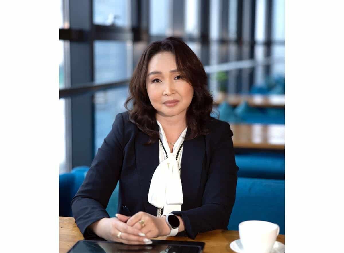 Урт хар үстэй, хөх өнгийн пиджак, цагаан цамц өмссөн эмэгтэй орчин үеийн гэрэлтэй кафед модон ширээний ард сууж байна. Тэр гараа урдаа атгаж, ширээн дээр аяга тавагтай. Өөртөө итгэлтэй бизнес эрхлэгч тэрээр камер руу шууд хардаг. - Business.MN