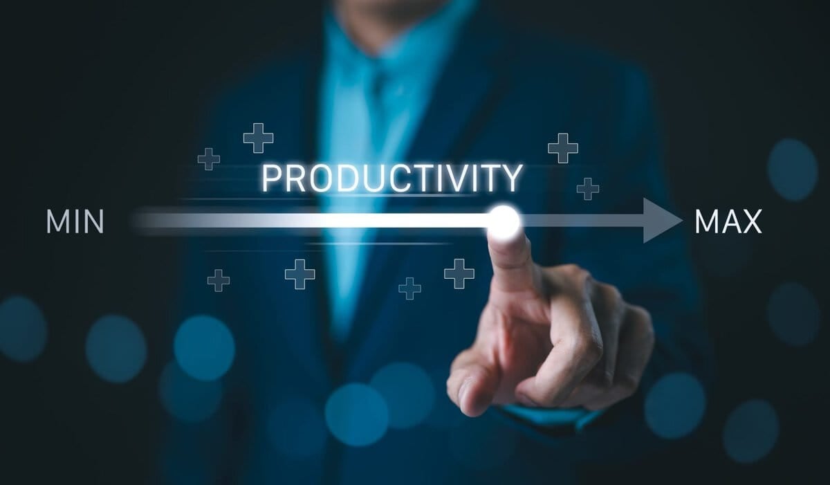 A person in a suit touches a glowing point on a digital slider labeled "Productivity," moving from "Min" to "Max," symbolizing increasing productivity with a blur of blue lights in the background.