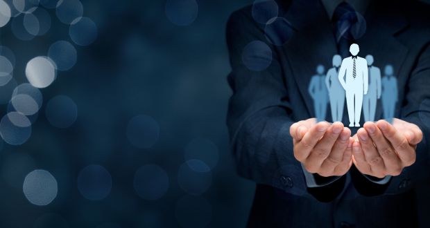 Костюм өмссөн хүн урд хэсэг нь тодорхой дүрслэгдсэн дүрс бүхий бүлэг дүрсний голограф дүрсийг барьдаг. Арын дэвсгэр нь бараан өнгөтэй, боке гэрлүүд нь манлайлах үзэл баримтлалыг санал болгож, эсвэл бусдаас онцгой хувь хүнийг сонгох болно. - Business.MN