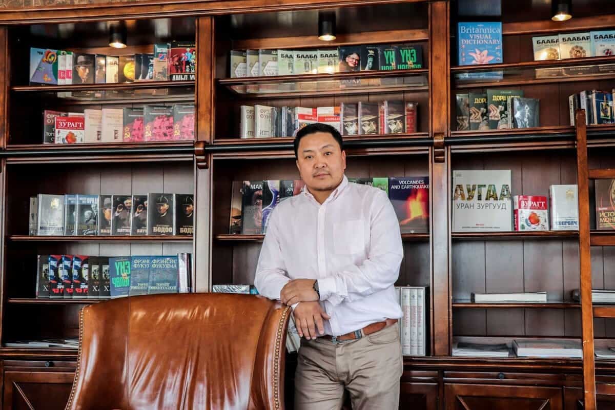 Цагаан цамцтай эр номын санд ардаа номын тавиуртай савхин сандлын хажууд зогсох нь энтрепренерийн дэгжин итгэлийг илтгэнэ. - Business.MN