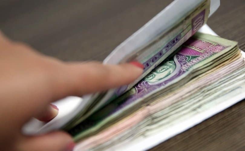 Энтрепренерийнх байх магадлалтай хумсаа будсан гар ширээн дээр тавьсан мөнгөн дэвсгэртийг гүйлгэж байна. Янз бүрийн мөнгөн дэвсгэртүүд нь цагаан дугтуйнд хэсэгчлэн хийгдсэн байдаг. - Business.MN