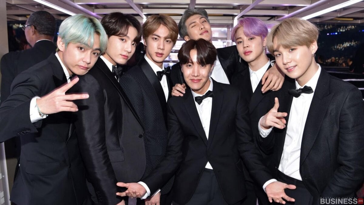 Смокинг өмссөн долоон эрэгтэй хамт зургаа татуулж, зарим нь энх тайвныг илтгэж, зарим нь инээмсэглэж байгаа нь компанийнхаа амжилтыг тэмдэглэхээр бизнесийн удирдагчдын эрч хүчтэй чуулга уулзалтад оролцож байна. - Business.MN