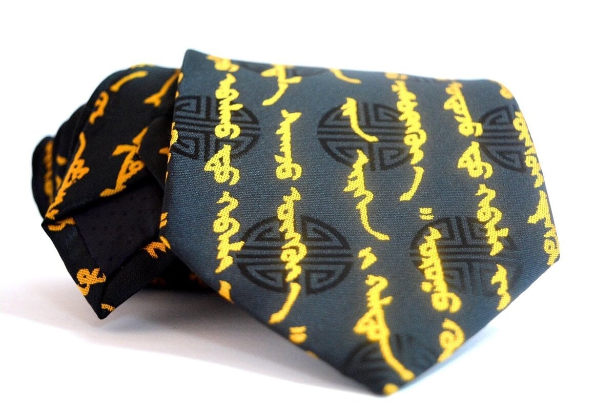 A black necktie featuring yellow script and circular decorative motifs, neatly rolled with the patterned design clearly visible against a white background.