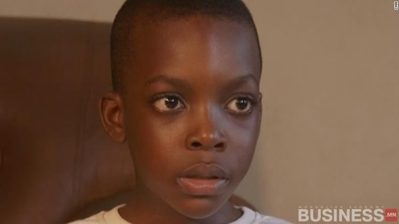 Ноцтой царайтай залуу хүүхэд бага зэрэг хажуу тийшээ хардаг. Тэд цагаан цамц өмсөж, дотор нь сууж байна. - Business.MN