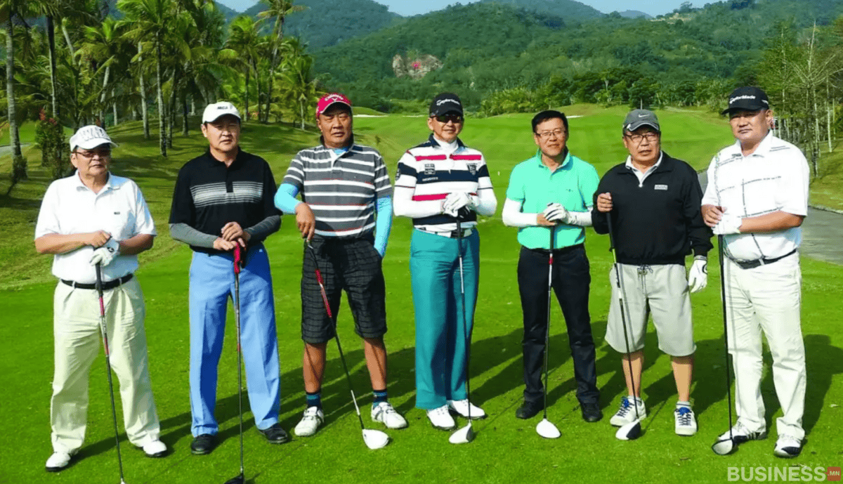 Гольфын хувцас өмссөн долоон энтрепренер эр гольфын талбай дээр цохиур барин зогсож, байгалийн үзэсгэлэнт ногоон дэвсгэр, ардаа уулстай. - Business.MN