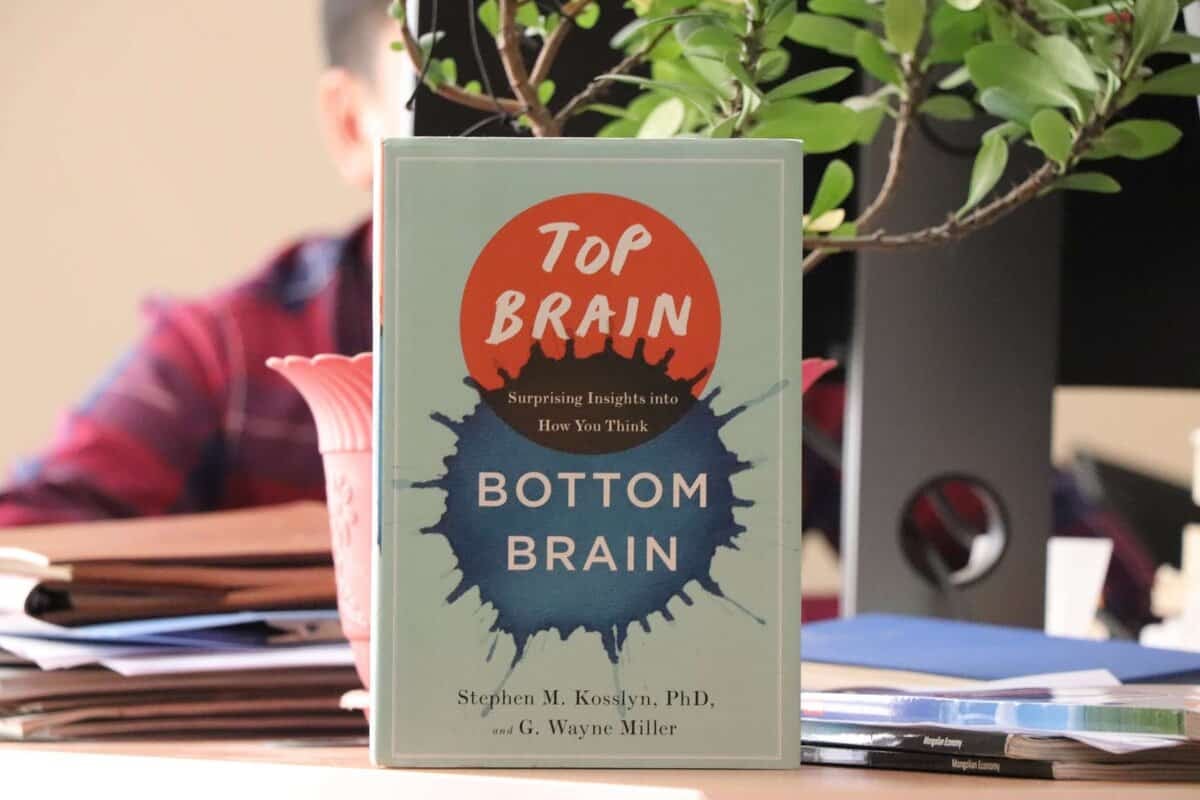 Доктор Стивен М.Косслин, Г.Уэйн Миллер нарын бичсэн "Дээд тархи, доод тархи: Таны хэрхэн бодож байгаа талаарх гайхалтай ойлголтууд" нэртэй номыг эмх замбараагүй ширээн дээр ургамлууд, цаас, ард нь бүдэг бадаг хүн байрлуулсан байна. - Business.MN