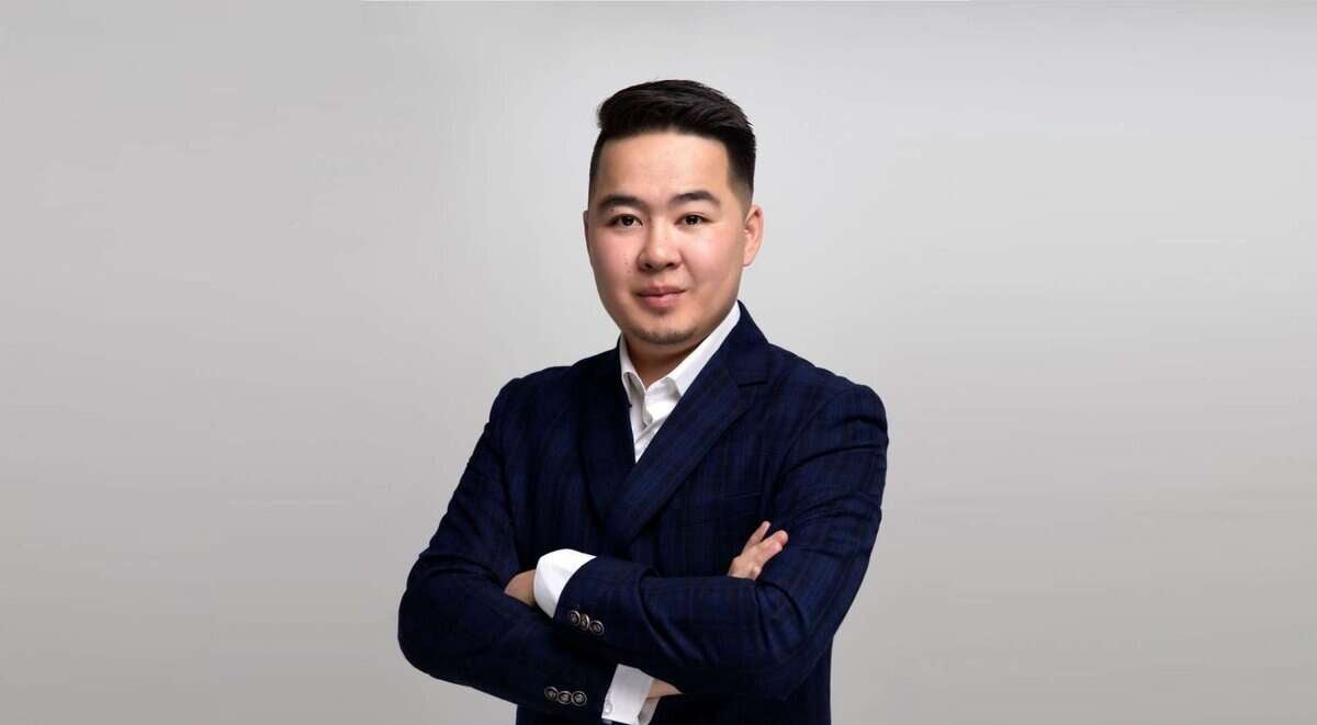 Харанхуй костюм өмссөн, гараа завилсан эр энгийн дэвсгэр дээр зогсож, компаниа удирдахад бэлэн энтрепренерийн итгэлийг илэрхийлж байна. - Business.MN