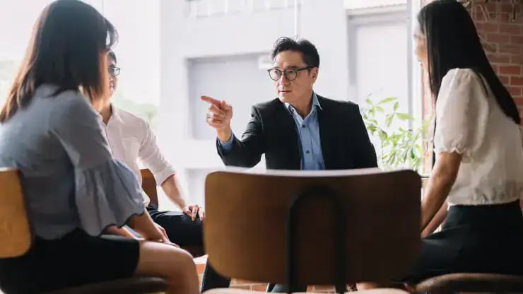 Дөрвөн хүний бүрэлдэхүүнтэй хэсэг оффисын орчинд хэлэлцүүлэг өрнүүлж байна. Костюм, нүдний шилтэй энтрепренер ярьж, гараараа дохиж байхад нөгөө гурав нь ажил хэрэгч энгийн хувцас өмсөж, анхааралтай сонсож байна. Тэд хагас тойрог хэлбэрээр байрладаг. - Business.MN