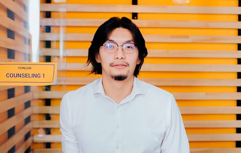 Шар модон дэвсгэр дээр "Зөвлөгөө 1" гэсэн бичээсийн өмнө нүдний шилтэй, сахалтай хүн зогсох нь энтрепренер хүний өөртөө итгэлтэй байдлыг илтгэнэ. - Business.MN