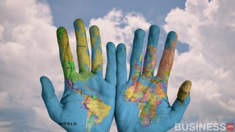 Үүлэрхэг тэнгэрийн дэвсгэр дээр алгаа урагш харсан, дэлхийн газрын зургаар зурсан хоёр гар нь компаний дэлхий дахины хүртээмж, энтрепренерийн сүнсийг бэлэгддэг. - Business.MN