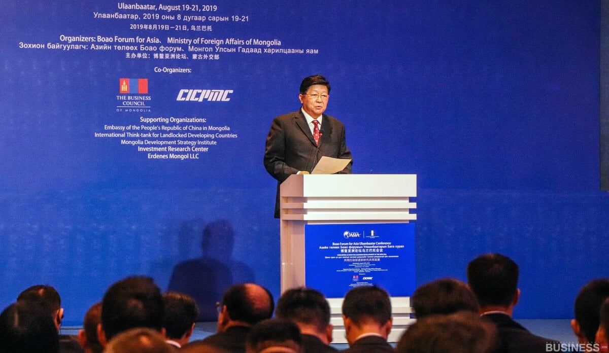 Монголын эдийн засгийн чуулга уулзалтад нэгэн эр индэр дээр үг хэлж байна. Арын дэвсгэр нь үйл явдлын дэлгэрэнгүй мэдээллийг олон хэлээр харуулдаг. - Business.MN