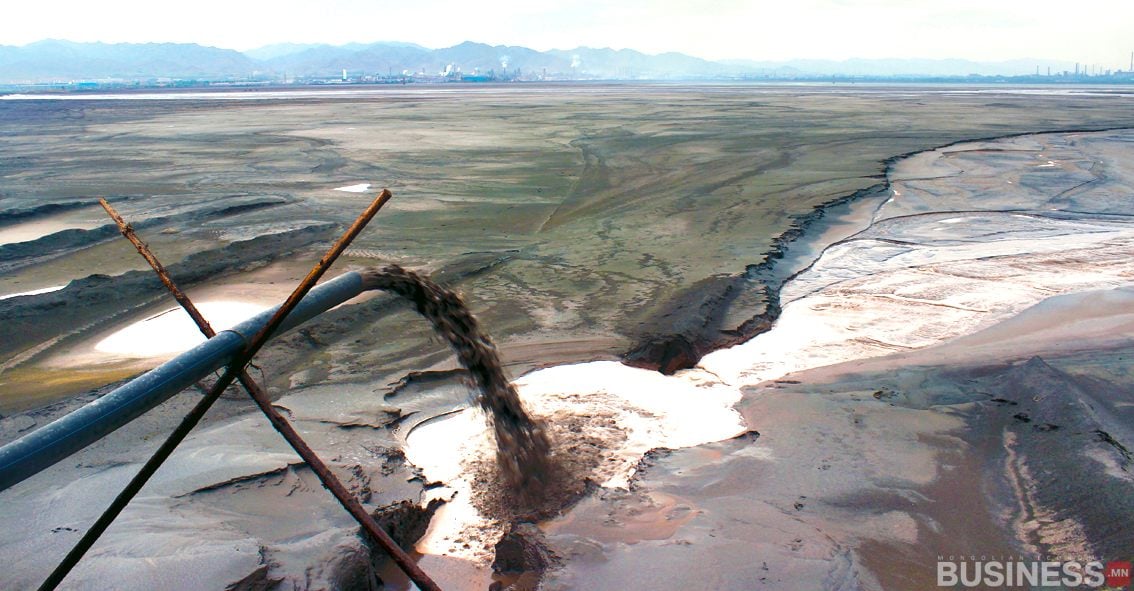 Том хоолой нь үйлдвэрийн хог хаягдлыг ардаа үйлдвэрийн барилга байгууламж бүхий үржил шимгүй, бохирдсон ландшафт руу асгаж байгаа нь тус компани байгаль орчныг үл тоомсорлож байгааг харуулж байна. - Business.MN