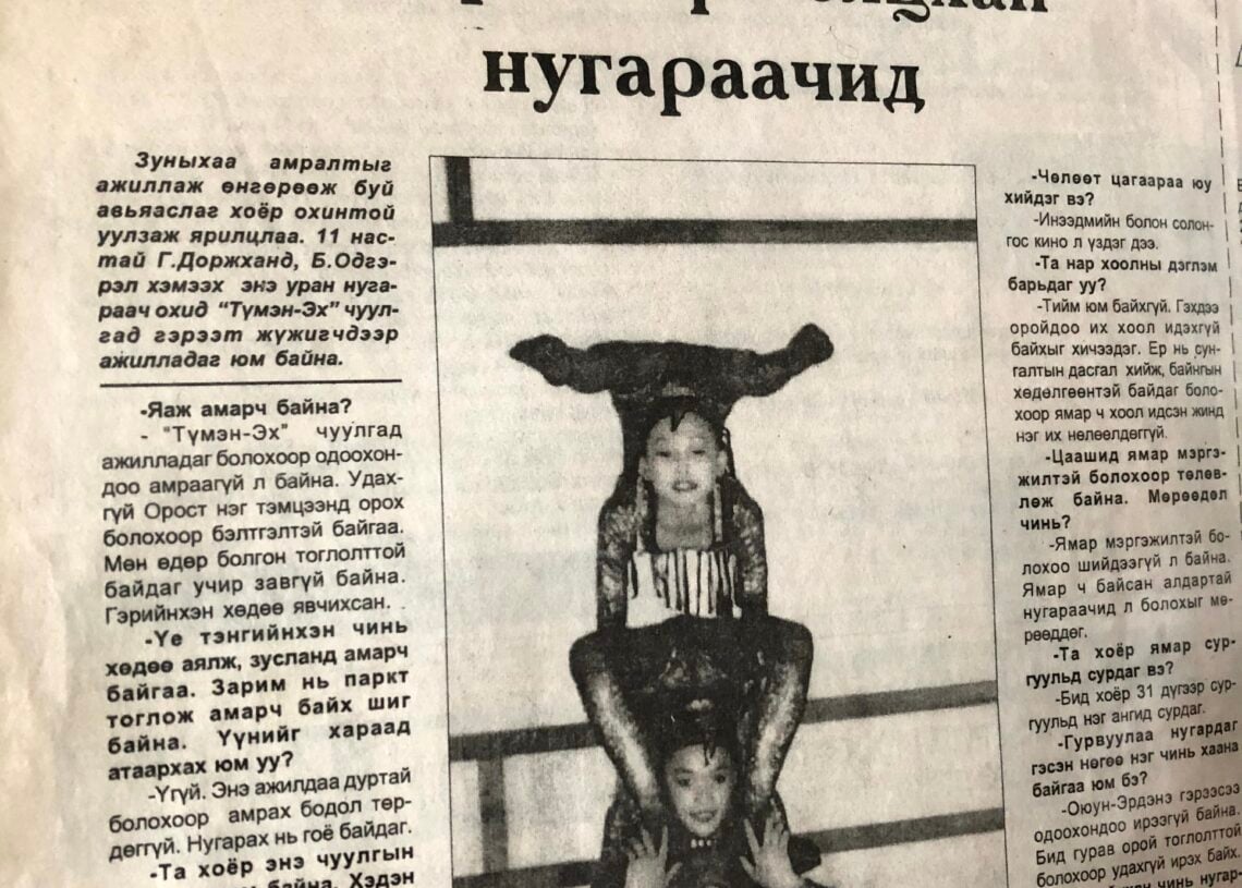 Монгол хэл дээрх нэгэн сонины хуудсанд Нарны циркийн дөрвөн жүжигчний тэнцвэртэй акробатын байрлалд овоолсон нийтлэл, хар цагаан гэрэл зураг нийтлэгдсэн бөгөөд хүн бүр дараагийнхыг нь дэмжиж байна. - Business.MN