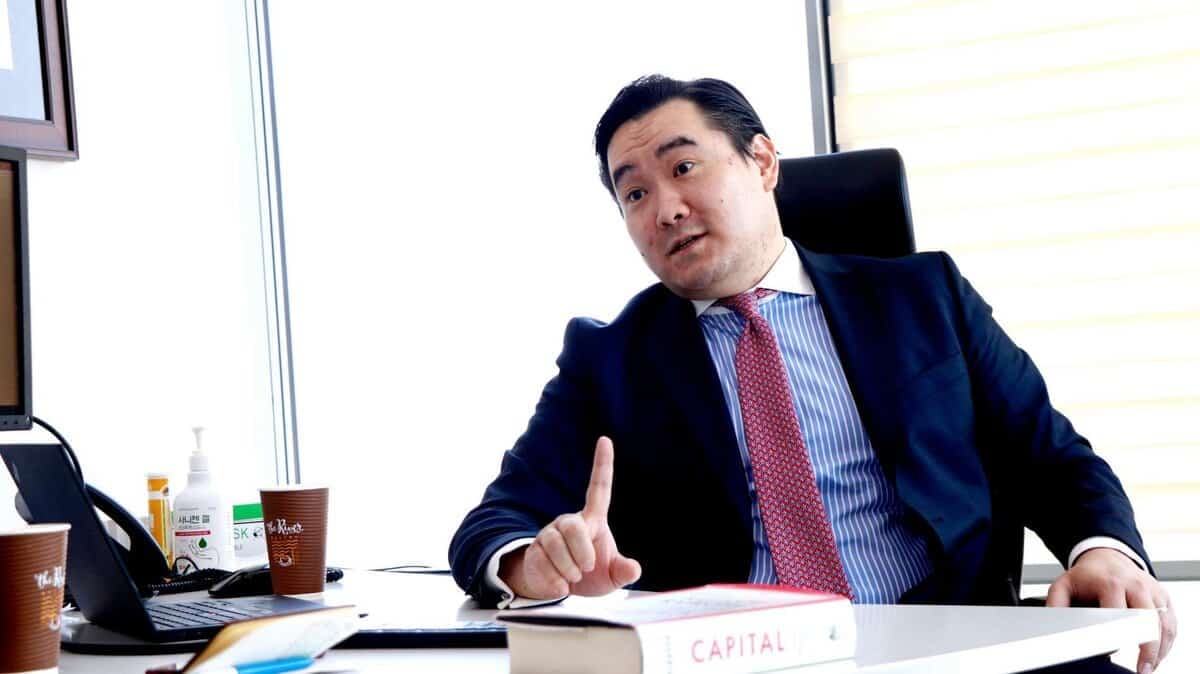 Костюм, улаан зангиа зүүсэн эр оффист суугаад долоовор хуруугаа дээш өргөн ярьж байна. "Капитал" нэртэй ном түүний ширээн дээр байгаа нь энтрепренерийн бизнесийг гүн гүнзгий сонирхож байгааг илтгэнэ. - Business.MN