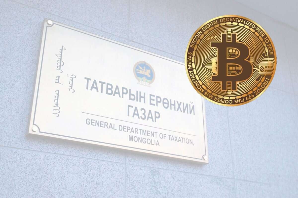 Цэнхэр ханан дээр "Татварын ерөнхий газар, Монгол Улс" гэж англи, монгол бичгээр бичжээ. Тэмдгийн хажууд орчин үеийн бизнесийн ландшафт дахь дижитал валютыг бэлэгддэг том биткойны зоосны дүрслэл байна. - Business.MN