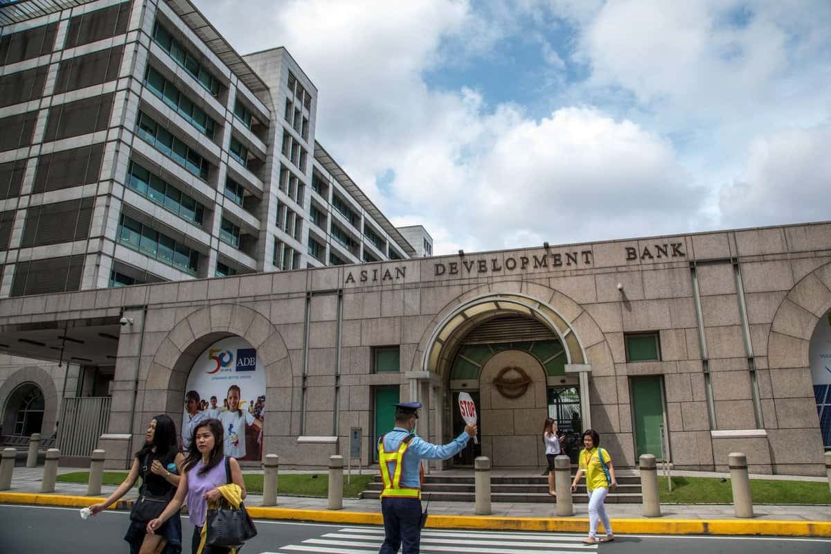 Азийн хөгжлийн банкны үүдэнд гудамжаар хөндлөн гарч буй хүмүүс, замын хөдөлгөөнийг удирдан чиглүүлдэг хамгаалалтын ажилтан, бизнес энтрепренерүүд чухал уулзалтууд руугаа чиглэдэг. - Business.MN