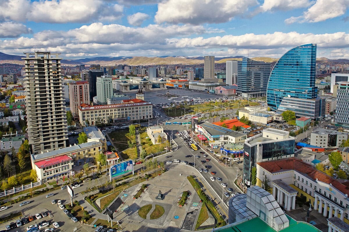 A cityscape view of Ulaanbaatar, Mongolia, where жижигрэх болон өсөлтийн үйл ажиллагаа нь орчин үеийн ба хуучны барилгууд, Монгол компаниудын идэвхтэй ажилтай гудамжууд дээр туссан байна. - Business.MN